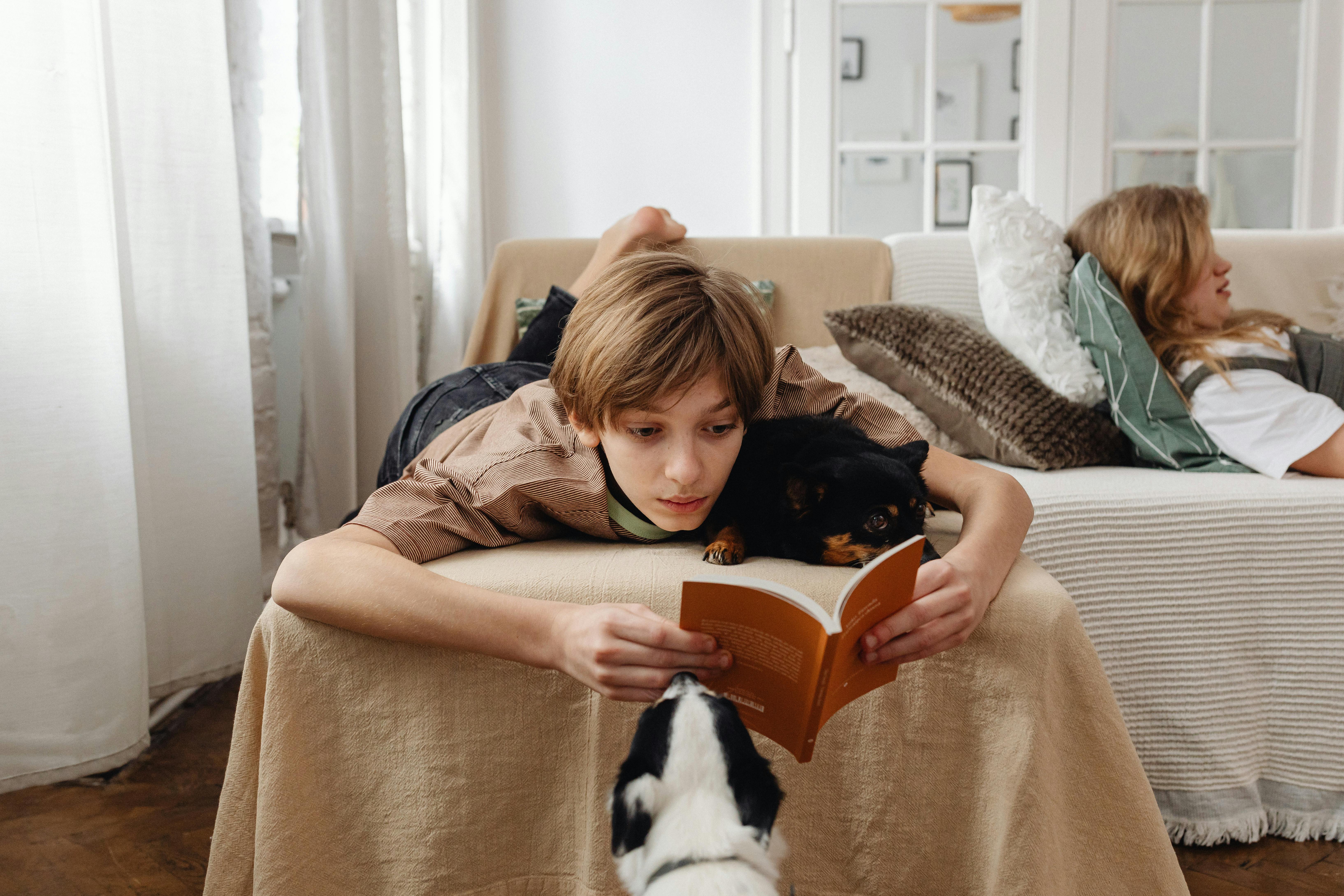 Boy laying on couch with his dogs and reading a book where they explain the future perfect tense in English