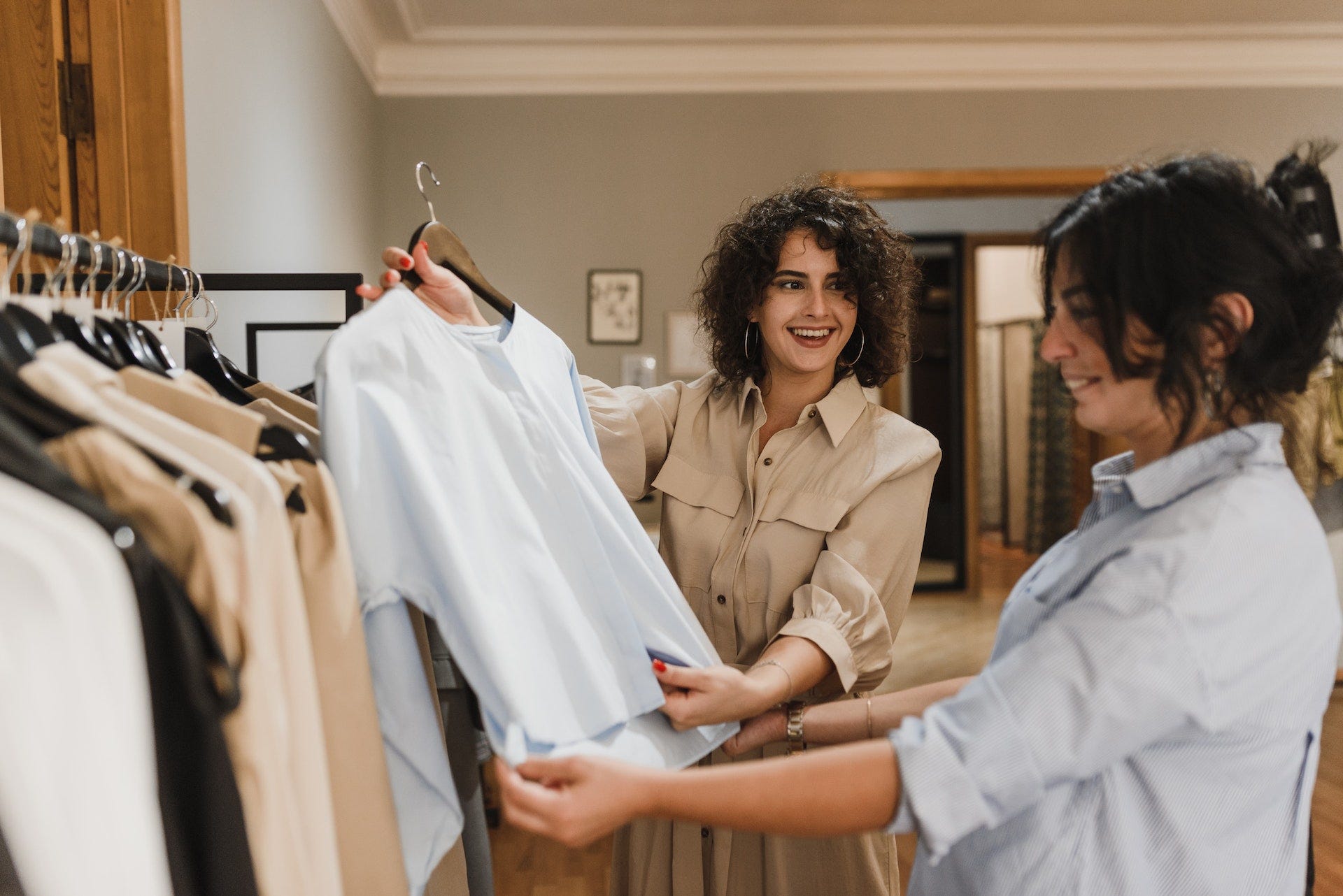 Woman looking at shirt in clothing shop asking English question words such as What size are you
